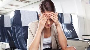 woman-in-plane-holding-her-head.jpg