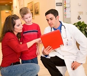 mom checking chart with son and doctor