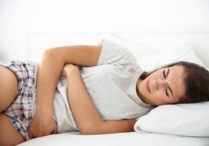 Woman Lying on Bed Feeling Constipated