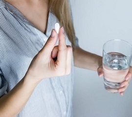 Woman Holding Glass of Water and Melatonin Supplement